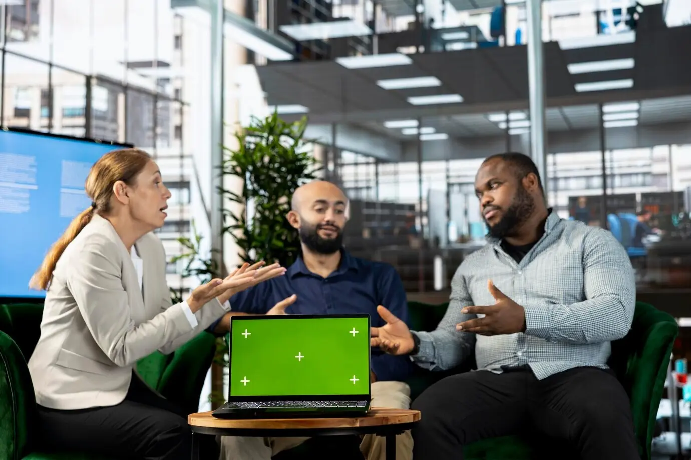 Изолированный экран планшета рядом с сотрудниками, изучающими исследовательскую документацию.